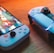 A gaming scenario featuring a smartphone with a game interface next to two controllers on a wooden surface. The smartphone displays vibrant images and icons, while the controllers feature a sleek, modern design with buttons and joysticks prominently visible. Warm lighting enhances the scene.